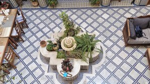 A courtyard with a tiled floor, a central fountain, and surrounding potted plants. - Dar Drissi (Fes)
