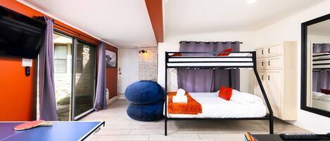 A compact room with a bunk bed, a ping pong table, and a pool table.