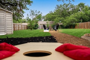 Un jardin avec une pelouse, une terrasse en bois et une zone délimitée par une clôture.