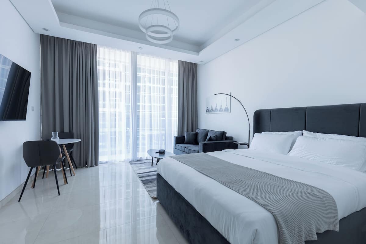 A modern hotel room with a large bed, a desk, and a sofa.