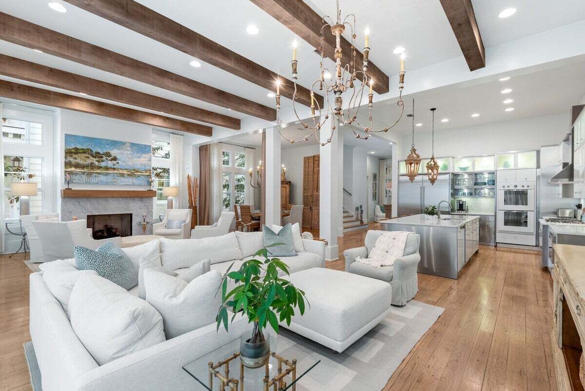 A spacious living room with a fireplace, white sofas, and a large window overlooking a scenic landscape.