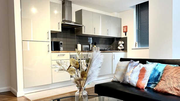 A modern kitchen with white cabinets, a stainless steel range hood, and a microwave. - Captivating 2-bed Apartment in Bedford (Bedford)