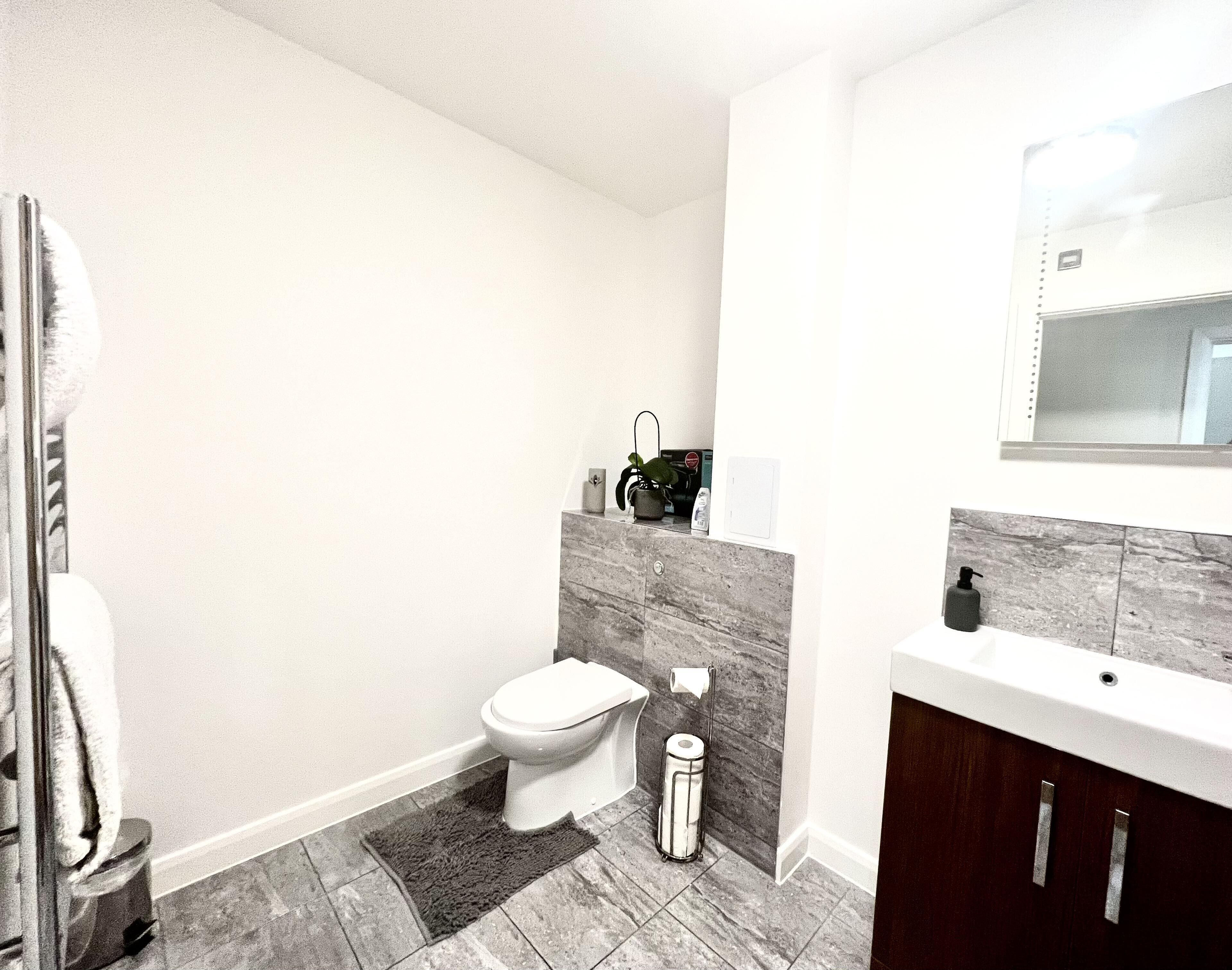 A modern bathroom with a toilet, bidet, and a sink with a mirror above it.