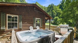 A wooden cabin with a hot tub, two Adirondack chairs, and a grill. - Cabin the the Gap- Motorcycle Friendly with Pond (Bryson City)