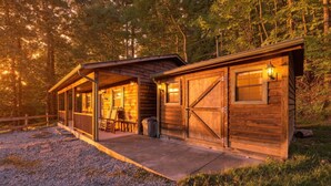 A wooden cabin with a porch, a covered seating area, and a garage door. - Cabin the the Gap- Motorcycle Friendly with Pond (Bryson City)