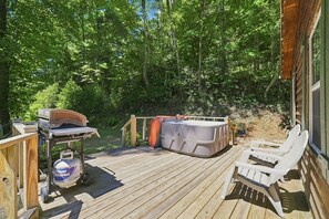 Eine Holzterrasse mit Whirlpool, Grill und Gartenmöbeln.