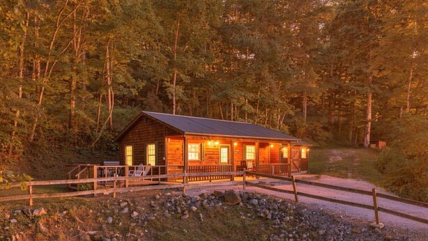 A wooden cabin with a porch, surrounded by a forest. - Cabin the the Gap- Motorcycle Friendly with Pond (Bryson City)
