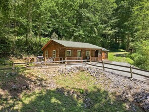 Eine Holzhütte mit Veranda, umgeben von Kies und einem Holzzaun.