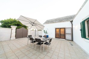 A patio with a table and chairs, a large umbrella, and a gate.