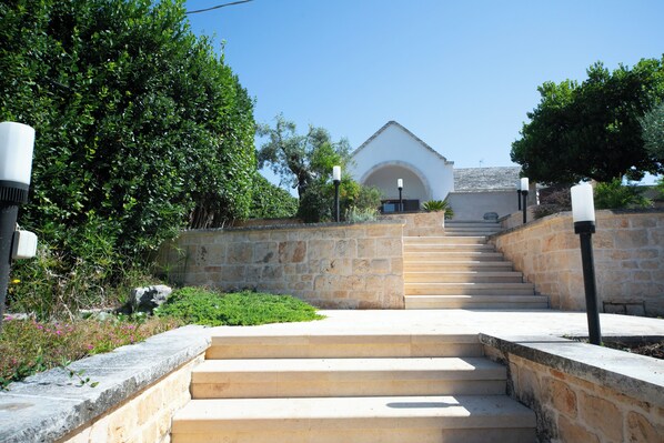 A stone staircase leading to a building with a white facade and an arched entrance.
