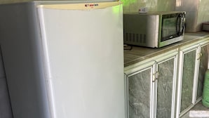 A kitchen with a white refrigerator, a microwave, and marble cabinets.