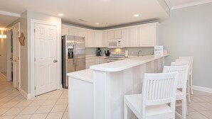 Una cocina moderna con armarios blancos, un refrigerador de acero inoxidable y un microondas integrado.