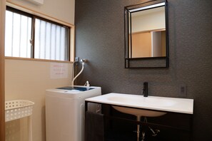 A bathroom with a white washing machine, a sink, and a mirror. - Mizukian (Kyoto)