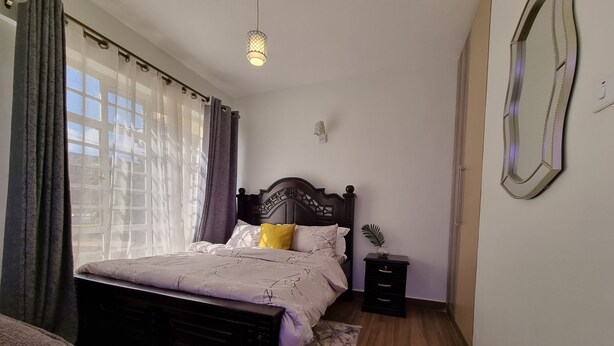 A bedroom with a bed, bedside table, and a nightstand. - Cozy Studio just 15 minutes to Karura Forest & 5 Minutes to Two Rivers Mall. (Ruaka)