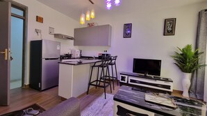 A compact living space with a kitchenette, a dining area, a seating area, and a TV. - Cozy Studio just 15 minutes to Karura Forest & 5 Minutes to Two Rivers Mall. (Ruaka)