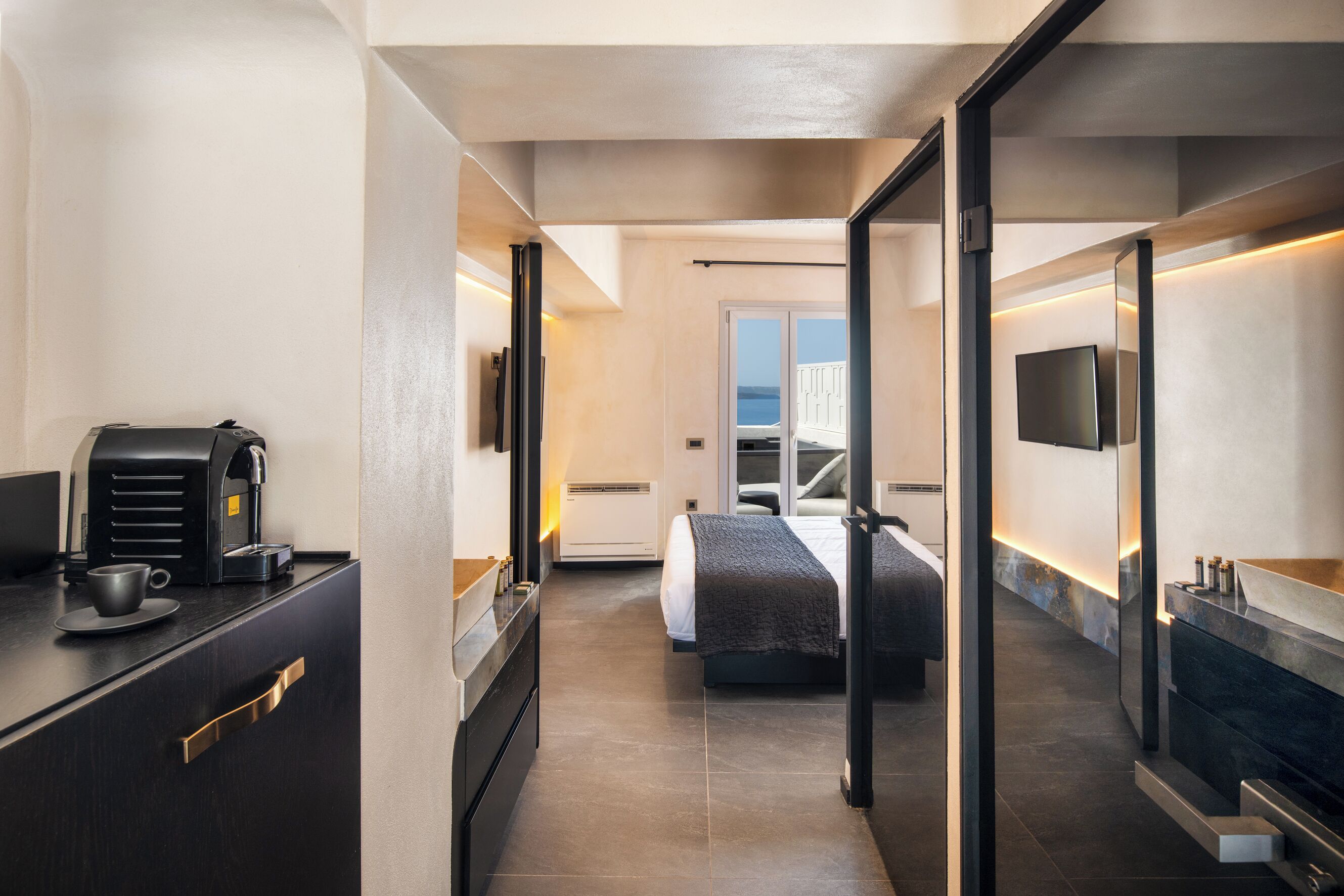 Une chambre d’hôtel moderne équipée d’un lit, d’une machine à café, d’une télévision et offrant une vue sur la mer.