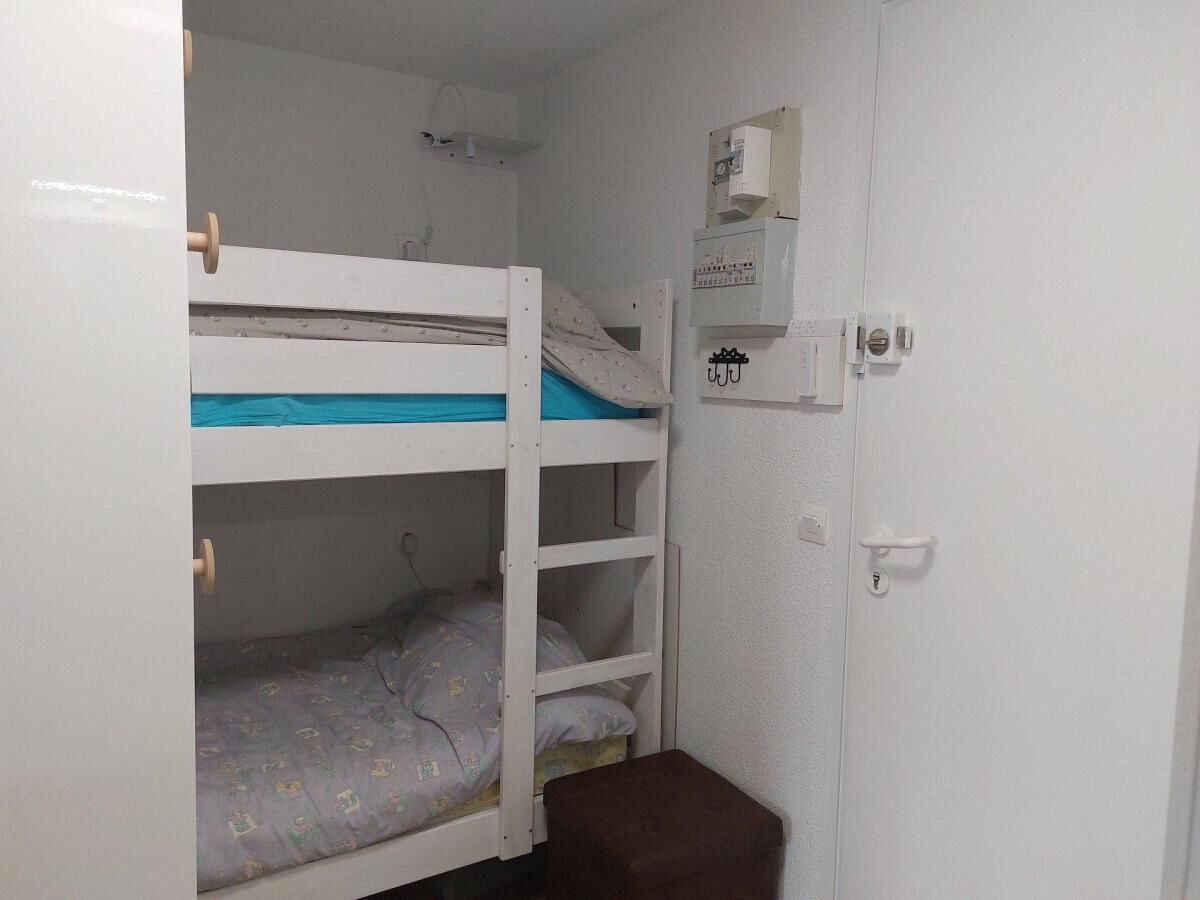 A small, compact room with bunk beds, a small table, and a door with a lock.