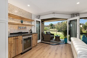 A modern kitchen with a glass door leading to a balcony with outdoor seating. - Fairway Haven - Luxury Carlsbad Golf Course Condo on the Omni La Costa Resort (Carlsbad)