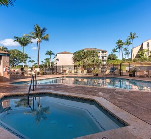 Relax by the rectangular pool surrounded by lounge chairs and umbrellas.