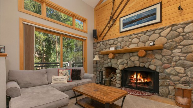 Una sala de estar acogedora con chimenea de piedra, un sofá gris y una mesa de centro de madera.