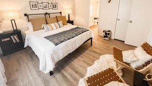 Quarto com cama, mesas de cabeceira, ventilador de teto, crânio de veado fixado na parede e uma porta.