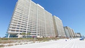 A high-rise hotel with multiple floors, balconies, and a beach view.
