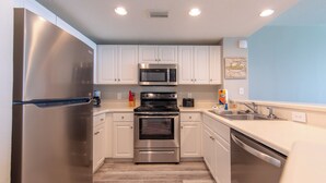 A modern kitchen with stainless steel appliances, white cabinetry, and a light blue accent wall.