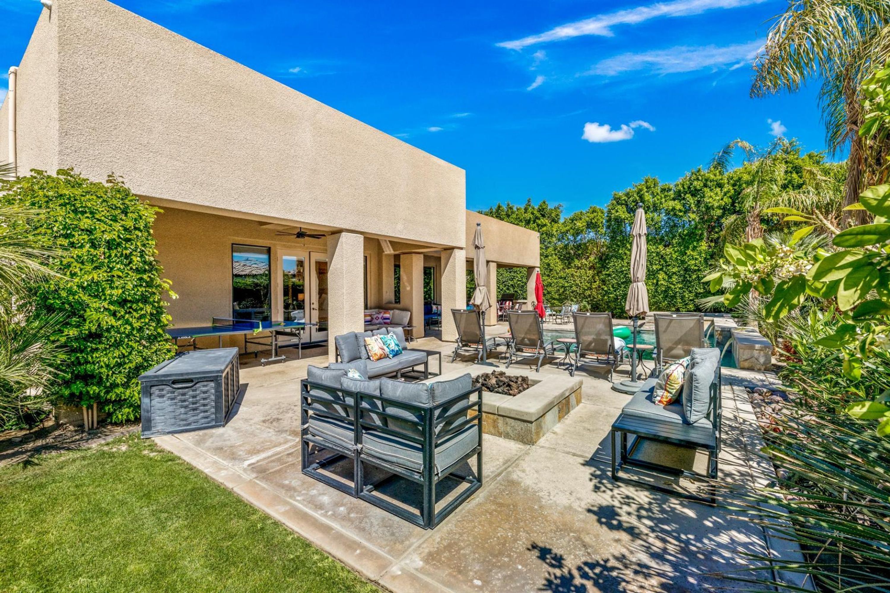Un patio con mobiliario exterior, piscina y abundante vegetación.