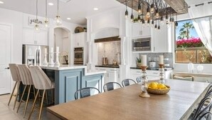 Una cocina moderna con armarios blancos, una isla central e iluminación colgante.