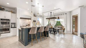 Una cocina moderna con una isla central, taburetes de bar y un comedor con vistas.