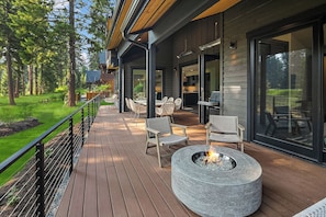 Una terraza de madera con mobiliario exterior y una chimenea.