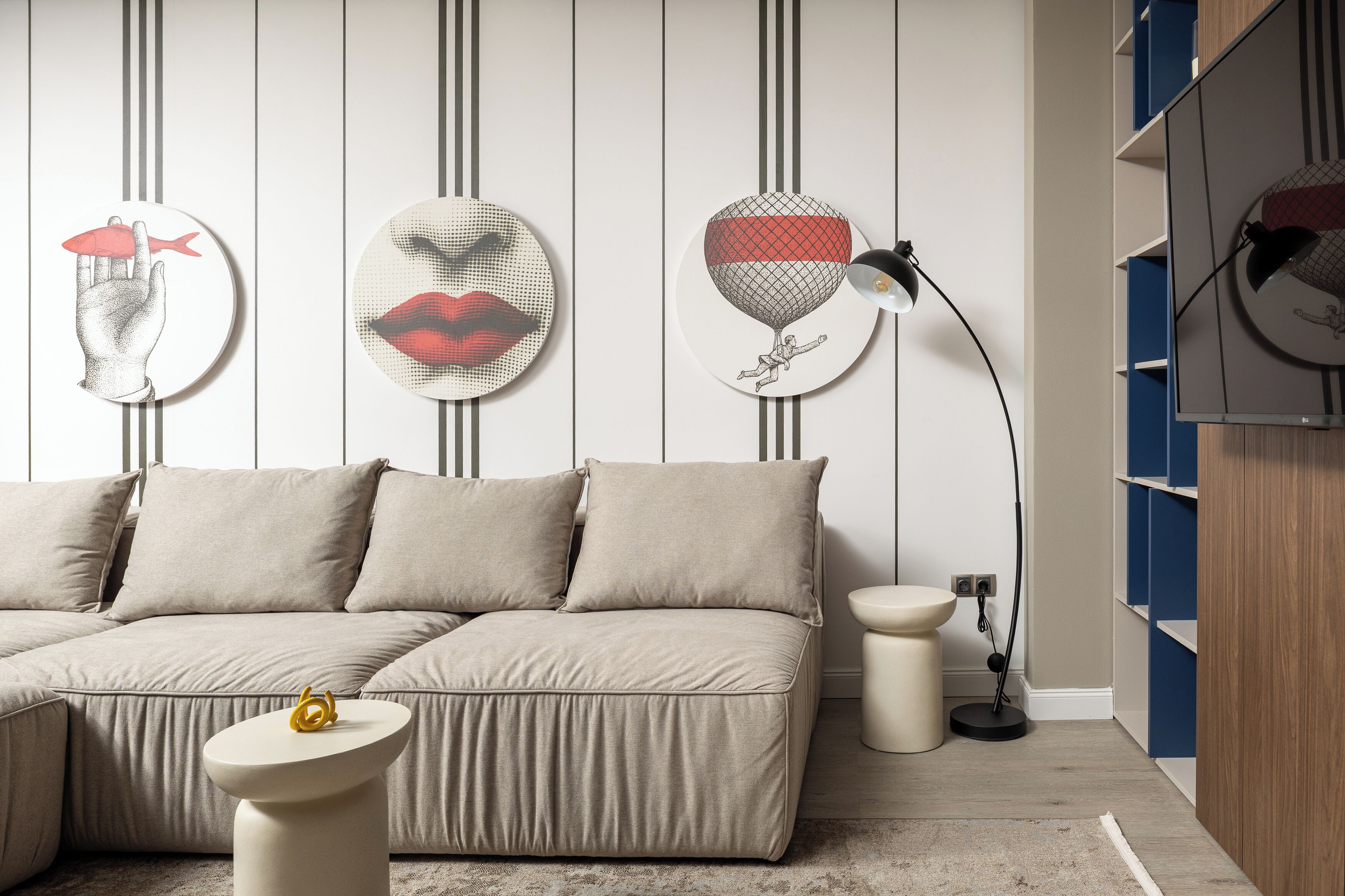 Un salon moderne avec un canapé d’angle, une petite table ronde et des œuvres d’art murales.