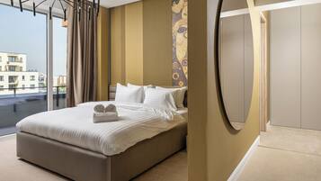 A modern hotel room with a large bed, a view of the city, and a unique wall design.