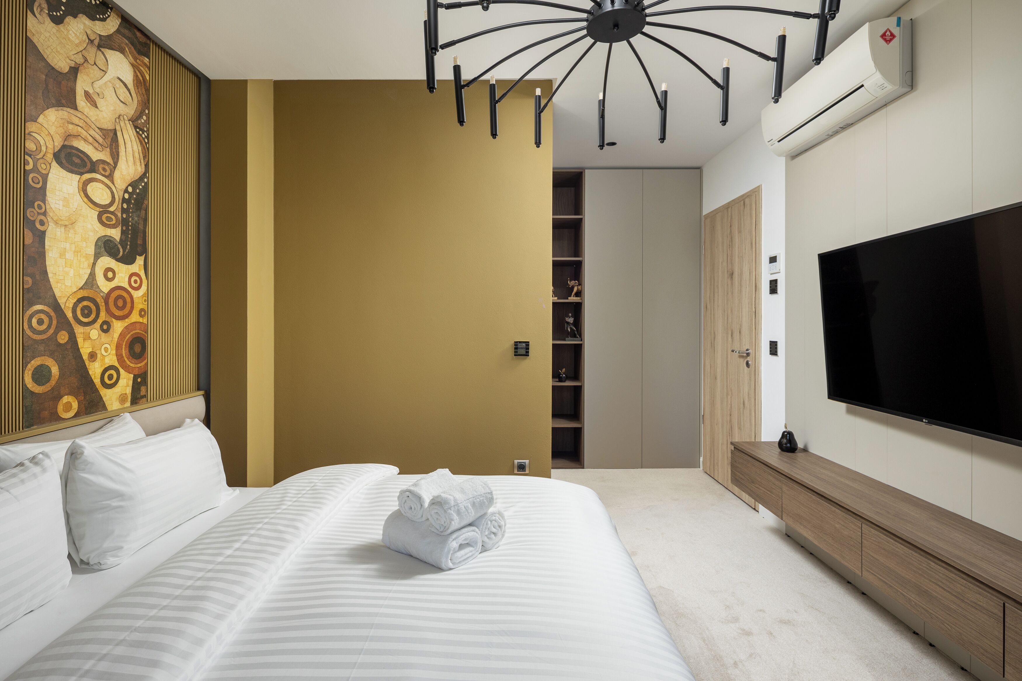 A modern hotel room with a large bed, a wall-mounted TV, and a decorative painting.