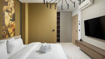 A modern hotel room with a large bed, a wall-mounted TV, and a decorative painting.