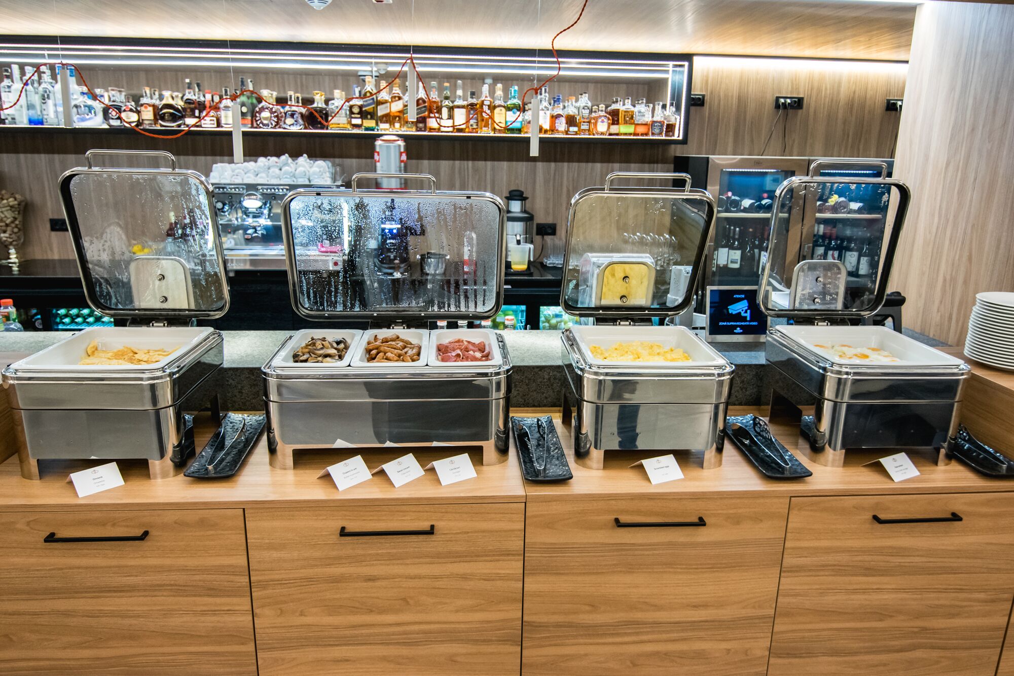 Zona de bufé con varias estaciones de comida y un bar al fondo.