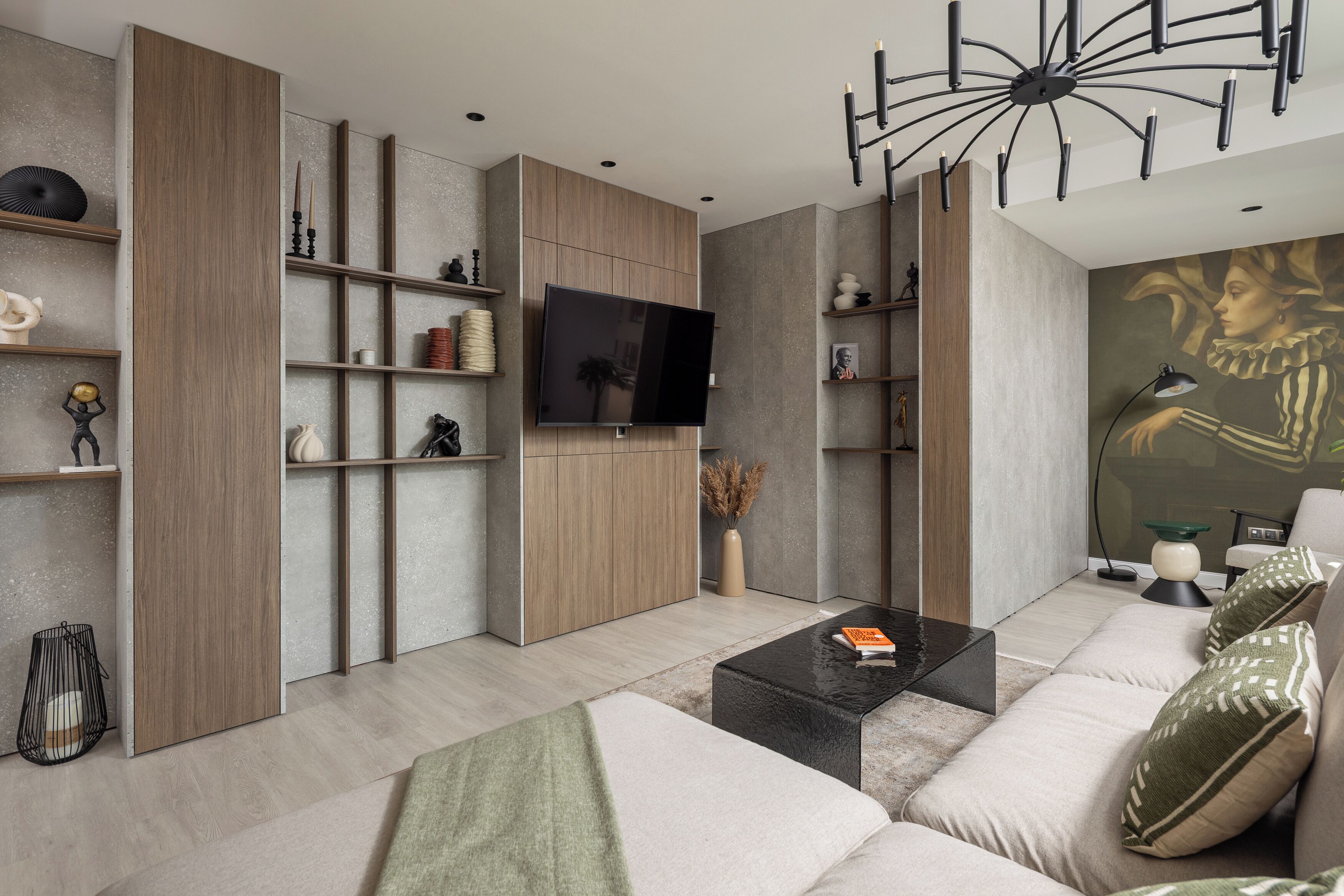 Een moderne woonkamer met een flatscreen televisie, houten planken, een zwarte salontafel en een bank met gekleurde kussens.