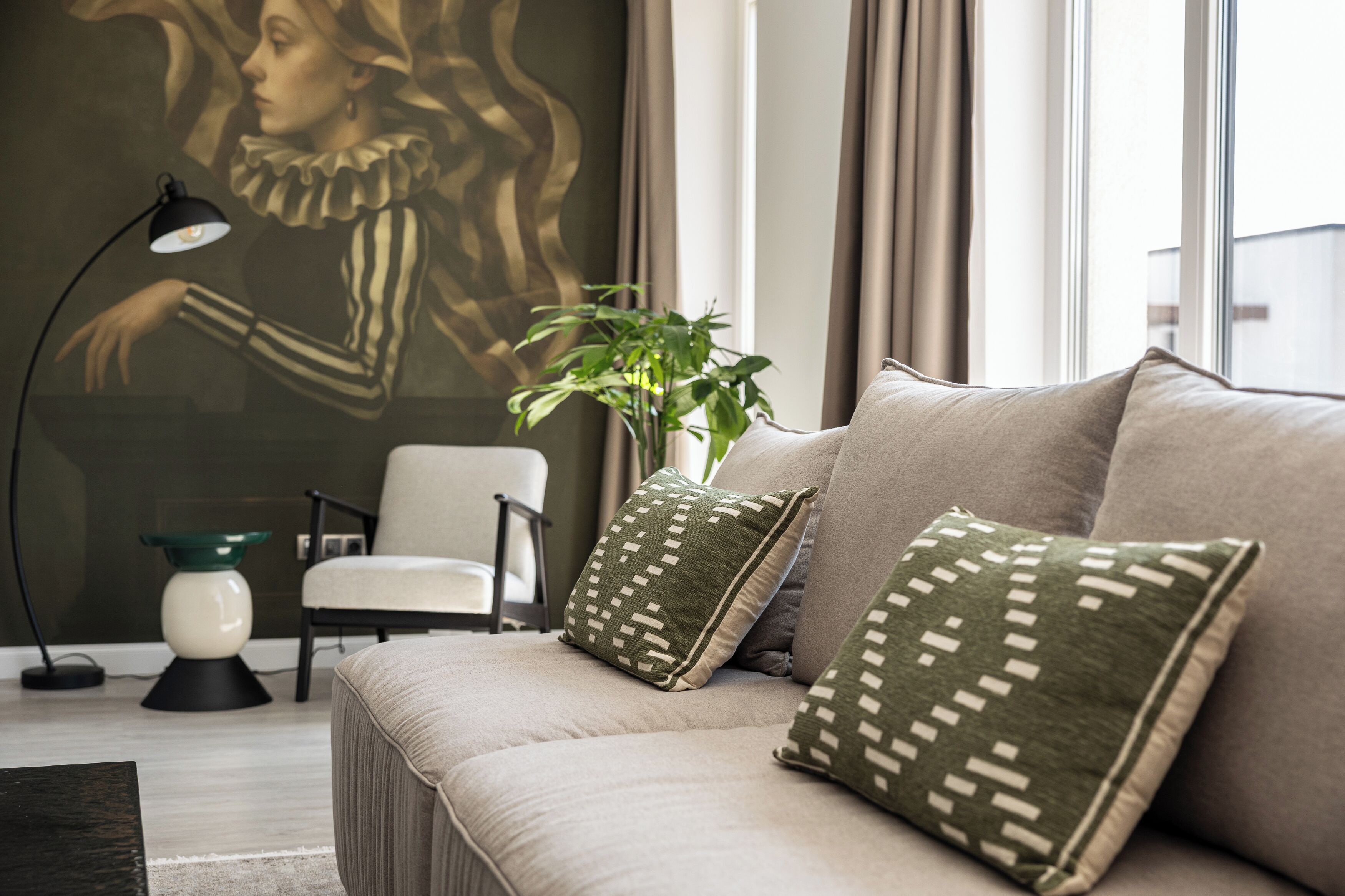 Una sala de estar moderna con un sofá, almohadones estampados, una lámpara de pie, un sillón y una planta verde.