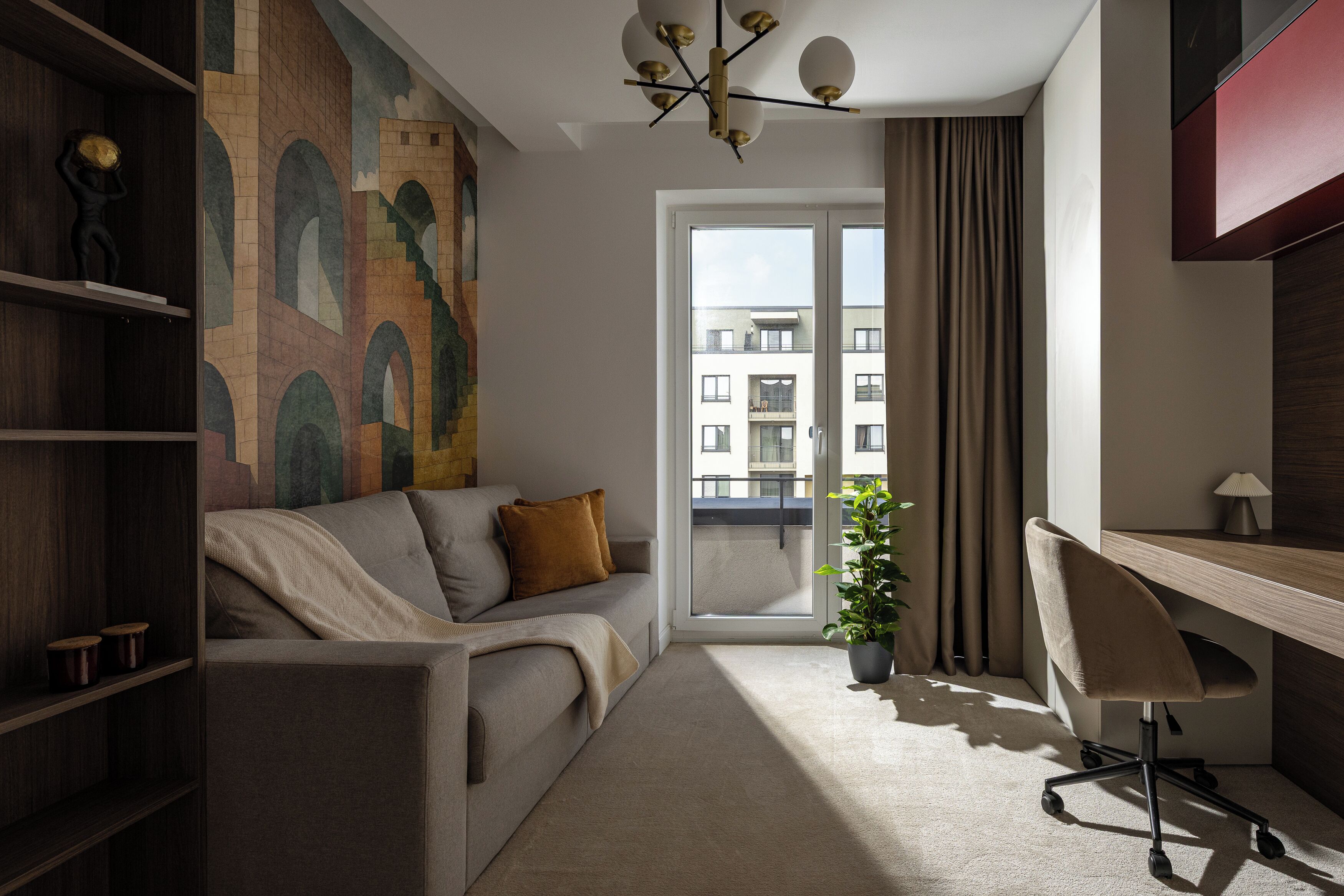 A modern living room with a sofa, a desk, and a large window.