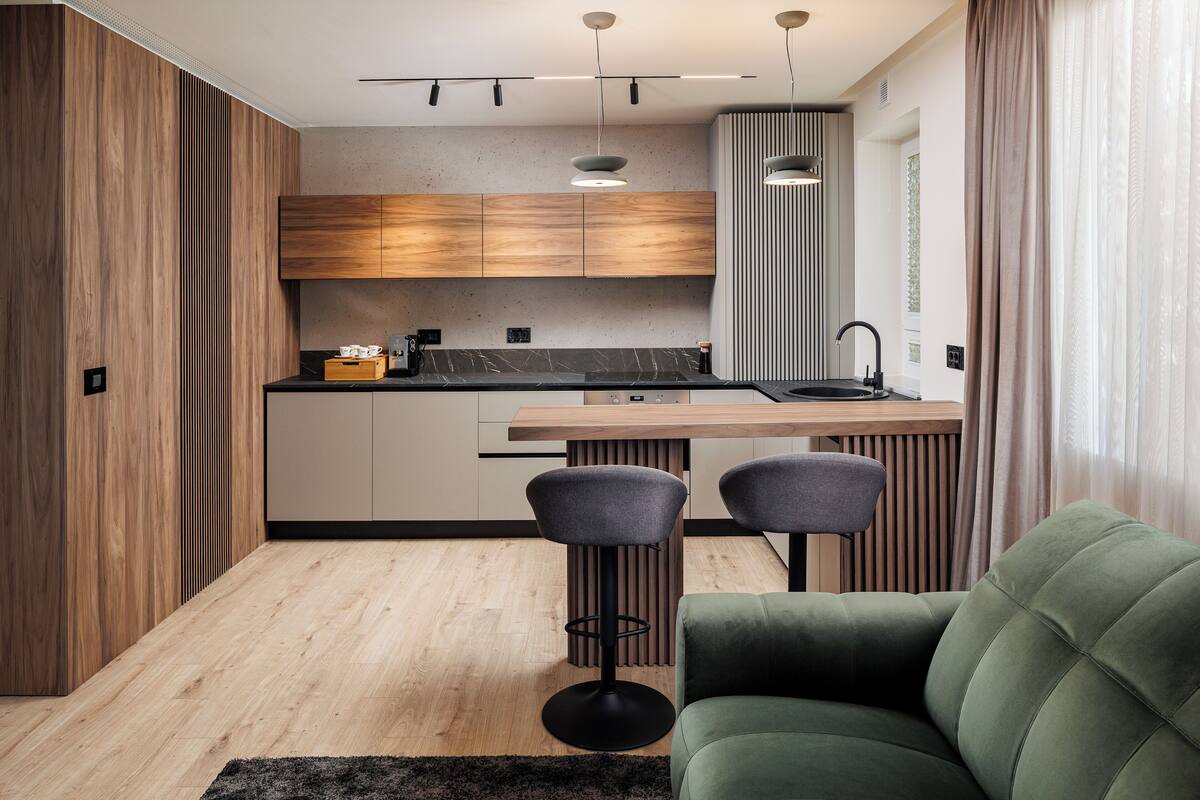A modern kitchen with wooden cabinets, a black countertop, and two bar stools.