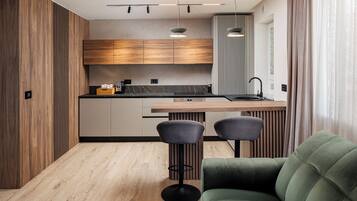 A modern kitchen with wooden cabinets, a black countertop, and two bar stools.