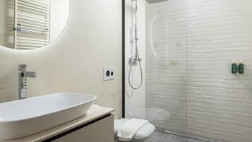 Ein Badezimmer mit einem weißen Waschbecken, einer Toilette und einer Duschkabine aus Glas.