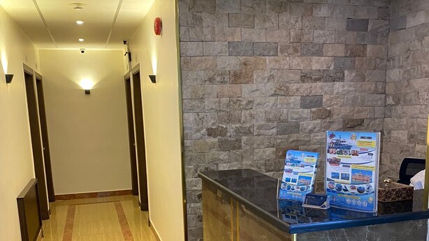 En hotellobby med en vägg av sten, en receptionsdisk och en korridor med dörrar.