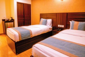 A hotel room with two beds, wooden headboards, and a small desk with a kettle. - Afnan Hotel (Aqaba)