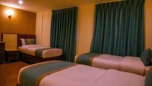Ett hotellrum med två sängar, en byrå och ett nattduksbord.