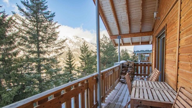 Un ponte di legno con vista su montagne innevate e alberi sempreverdi.