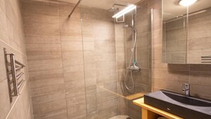 Un bagno moderno con cabina doccia in vetro, mobile lavabo in legno e un ampio specchio.
