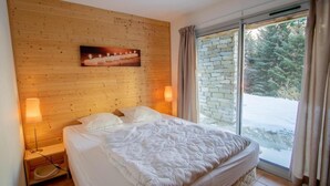 Una camera da letto con un letto grande, pareti in legno, una finestra con muro in pietra e vista su un paesaggio innevato.