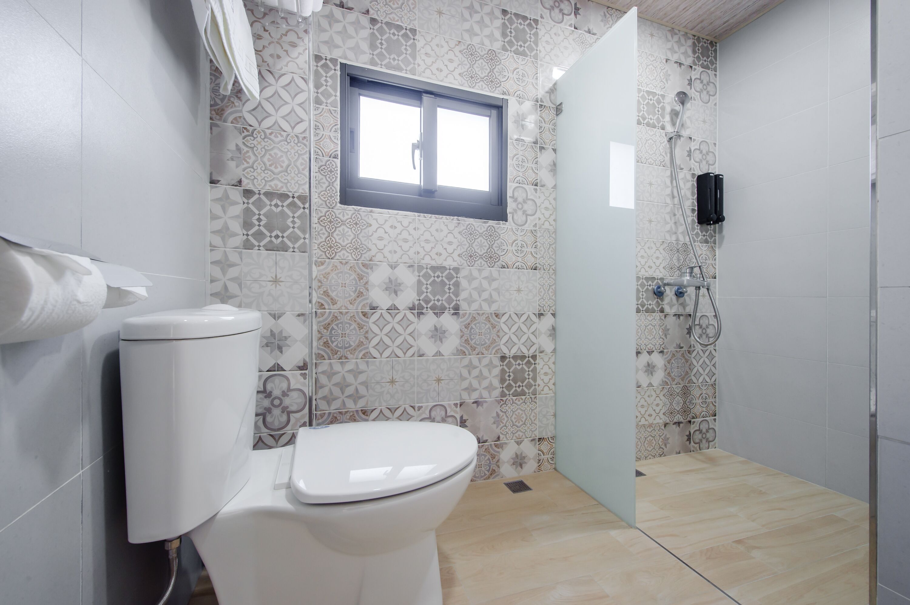 Un baño con inodoro, ventana y zona de ducha.