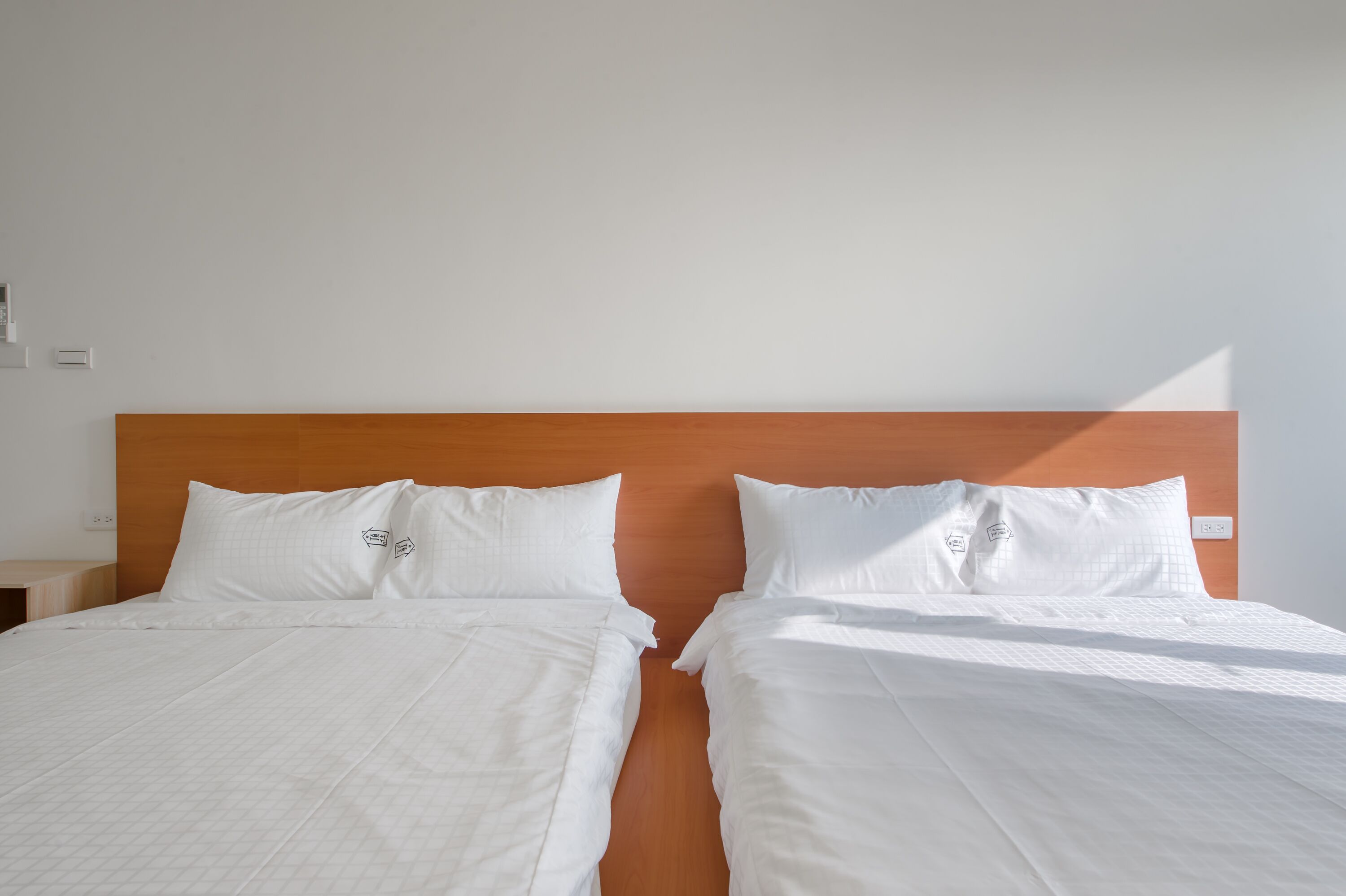 Een hotelkamer met een tweepersoonsbed, wit beddengoed en een houten hoofdbord.